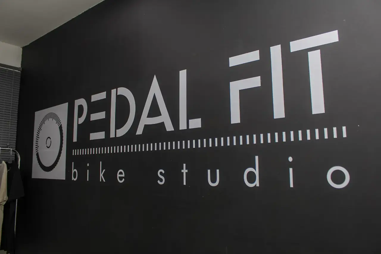 Parede preta com o logo Pedal Fit Bike Studio